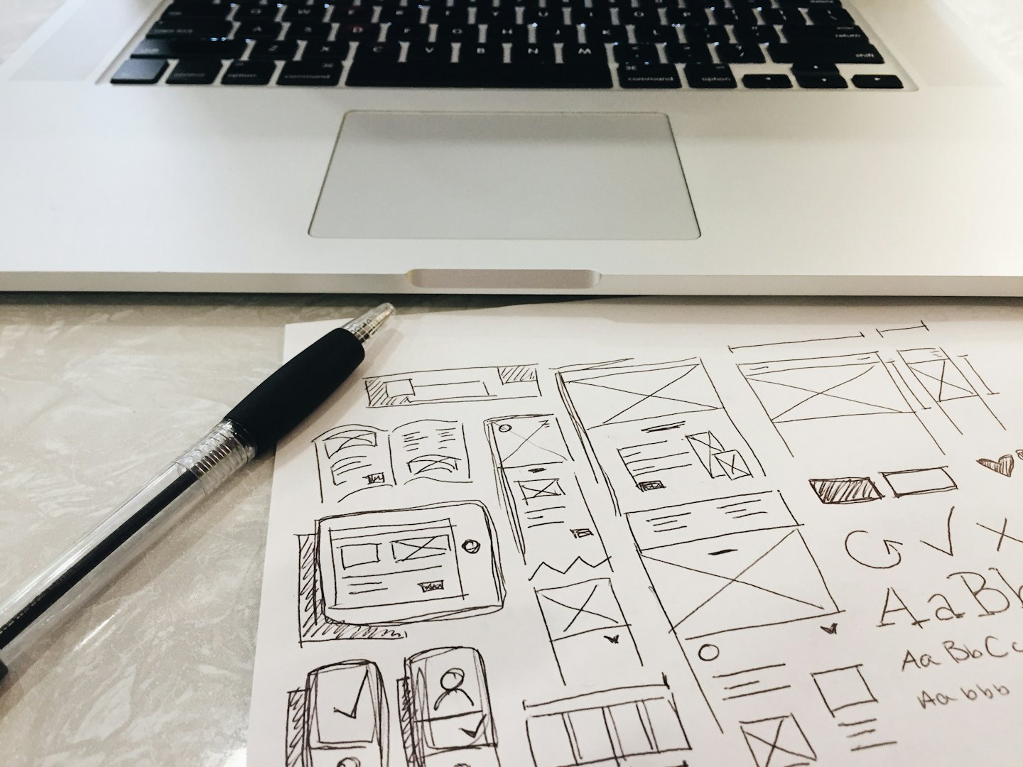 Hand-drawn UI wireframes and sketches on paper with a pen.