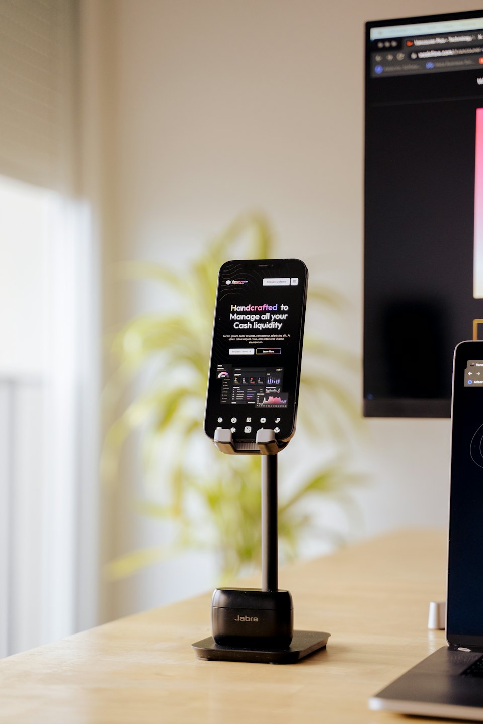 Smartphone on a stand showing business dashboard on a desk.